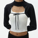 Woman wearing a black cardigan over a white top with a black bow on a white background